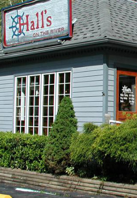 Blue restaurant building with grey roof and a sign with a red border and ship's wheel as the logo.