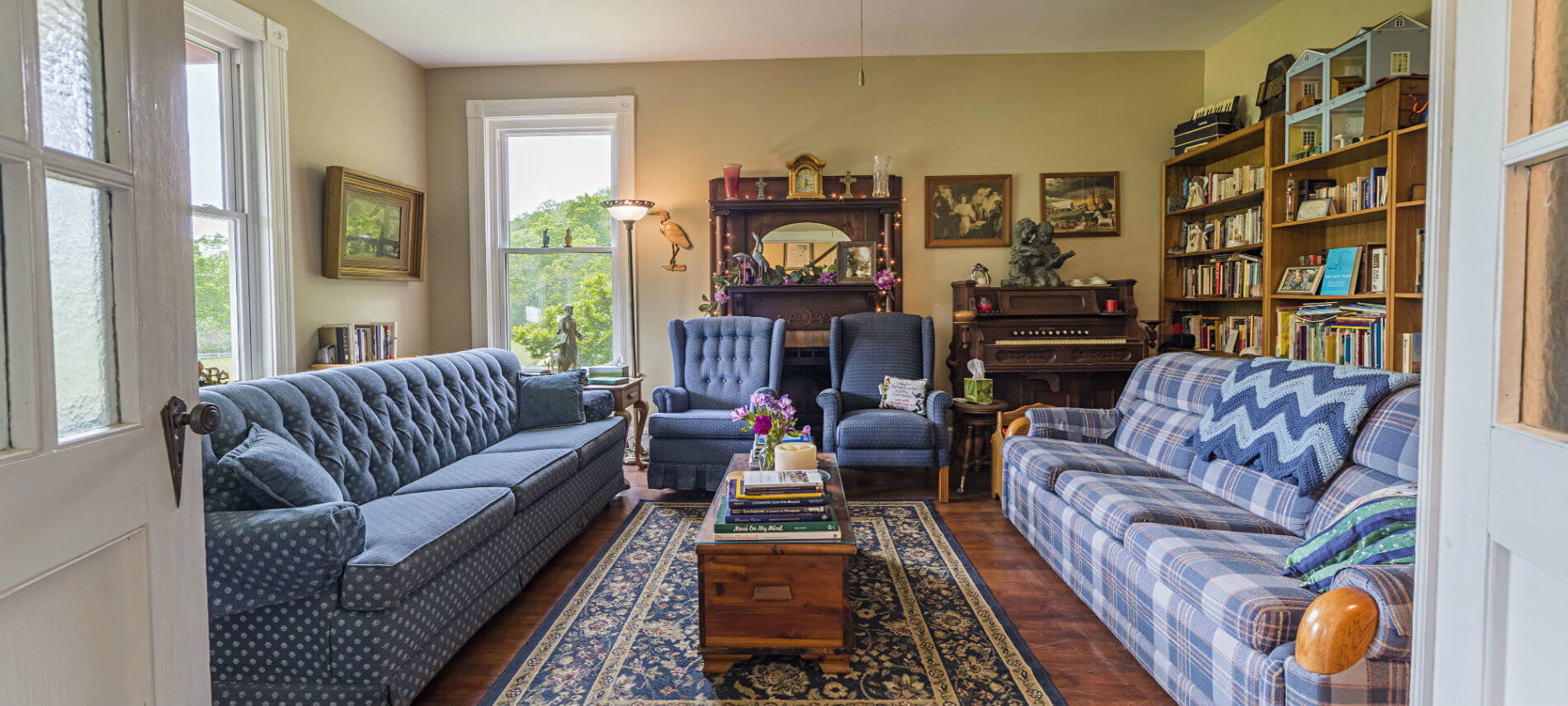 Two comfortable blue sofas and two easy chairs create a cozy space for conversation or reading in the library.