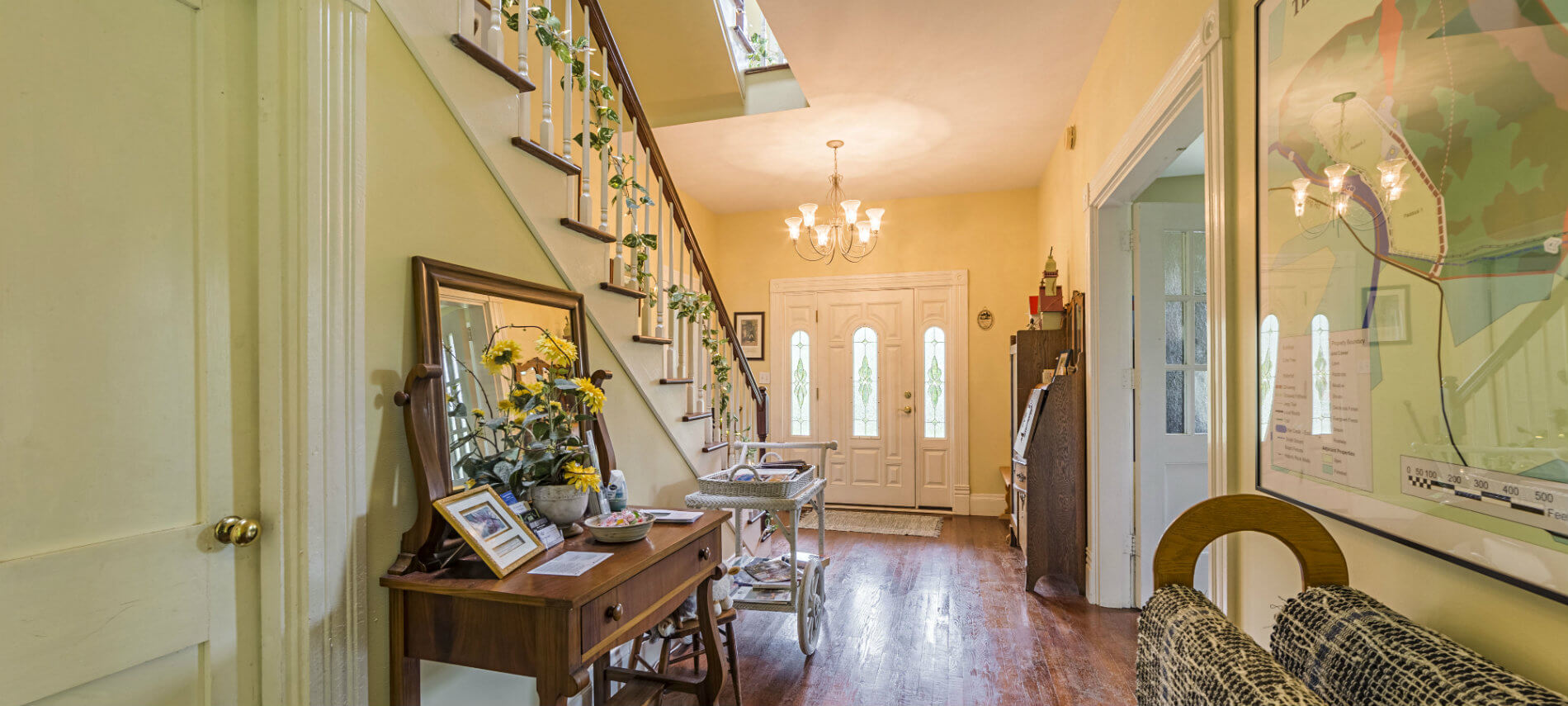 A bright entrance hallway displays blue rag rugs, chandelier and stairway to second floor