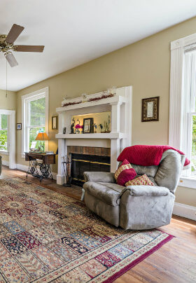 The Living Room has two chestnut sofas, several comfortable recliners, an oriental rug and a fireplace.